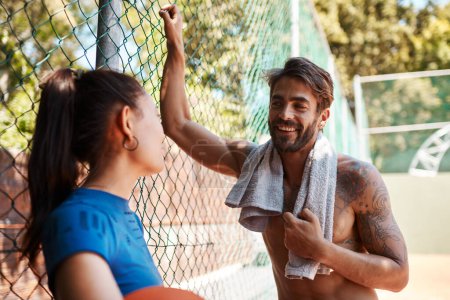 Photo for You could teach me a thing or two about basketball. two sporty young people chatting to each other against a fence on a sports court - Royalty Free Image