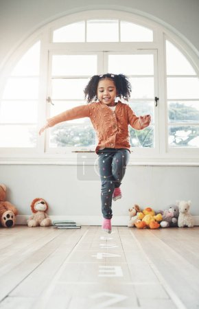 Photo for Hopscotch, happy and girl play in home having fun, enjoying games and relax in bedroom. Childhood, kindergarten and excited child balance for jumping game, playing and entertainment activity on floor. - Royalty Free Image