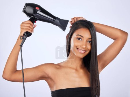 Indian woman, hair care or dryer in studio portrait for healthy natural shine, styling or wellness. Face of glowing happy girl model, salon or self care cosmetics in grooming on white background.