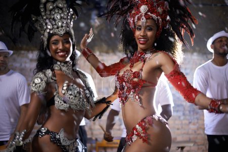 Turning beats into heat. two beautiful samba dancers performing in a carnival with their band