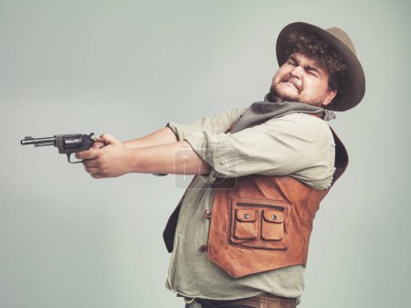 Foto de Eso no parece muy difícil de golpear... un vaquero desafortunado con sobrepeso disparando su pistola mientras cierra los ojos - Imagen libre de derechos
