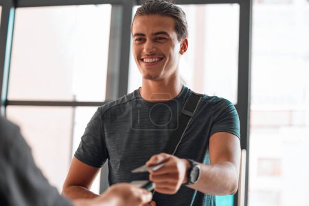 Credit card, man smile and payment at gym for fitness membership or exercise subscription. Fintech pos, ecommerce and happy athlete buying or paying for workout or training bill at exercising club