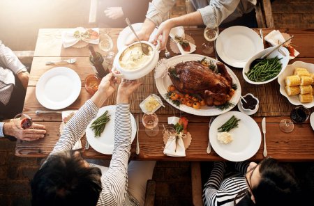 Photo for There wont be any leftovers at this table. High angle shot mash being passed around during a feast at a dining table on Thanksgiving - Royalty Free Image