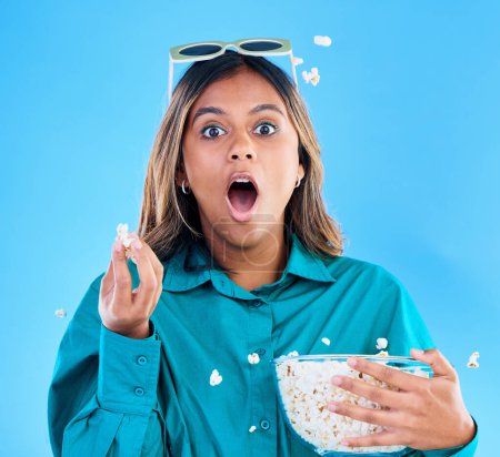 Photo for 3D glasses, popcorn and wow with a woman in studio on a blue background looking shocked while eating a snack. Portrait, movie and video entertainment with an attractive young female feeling surprised. - Royalty Free Image