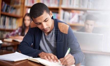 Foto de Trabajando diligentemente. un joven estudiante guapo trabajando diligentemente en su aula - Imagen libre de derechos