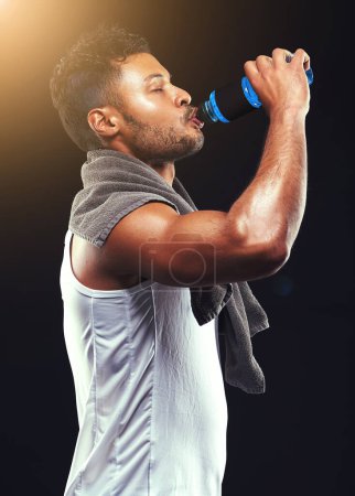 Photo for Rehydrating after an epic workout. Studio shot of a fit young man isolated on black - Royalty Free Image