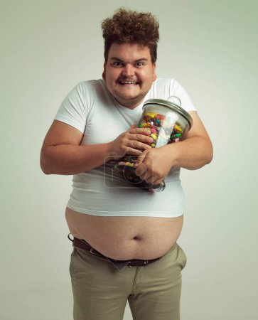 Photo for Time for a sugar rush. an overweight man holding a large jar of candy - Royalty Free Image