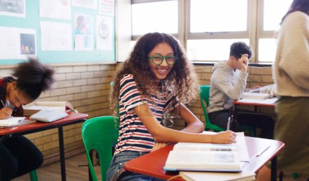 Photo for Shes gonna ace the exams. Portrait of a cheerful young school kid seated at her desk while doing work inside of a classroom at school - Royalty Free Image