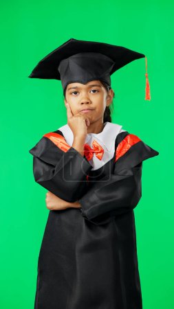 Photo for Graduation, education and thinking child on green screen for graduate, academy ceremony and award. Primary school, student and portrait of young girl with knowledge, achievement and success in studio. - Royalty Free Image