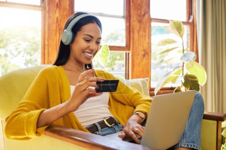 Frau, Laptop und Kreditkarte mit E-Commerce und Kopfhörer, um beim Online-Shopping Musik zu hören. Glückliche Frauen entspannen zu Hause, Podcast oder Radio-Streaming mit Fintech, Internet-Banking und Bezahlung.