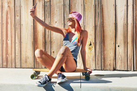 Photo for Im tagging my skater buddies on this one. a young woman taking a selfie while sitting on her skateboard - Royalty Free Image