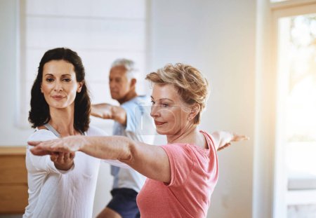Ponerse en forma a través del yoga. un profesor ayudando a una mujer mayor durante una clase de yoga