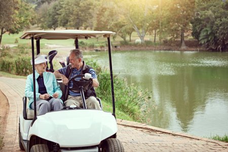 Driving between drives. a smiling senior couple riding in a cart on a golf course