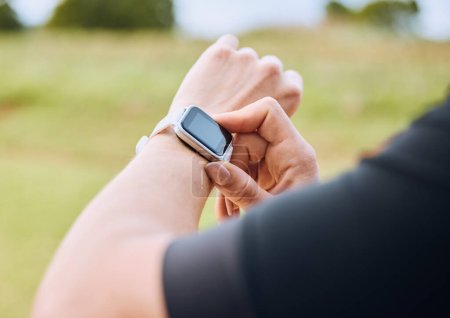 Hands, training and smart watch with a sports person outdoor, checking the time during a workout. Arm, exercise and technology with an athlete tracking cardio or endurance performance for fitness.
