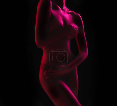Neon, seductive and the body of a woman in the dark isolated on a black background in a studio. Sexy, art and a girl covering with a purple glow for creativity, mystery and artistic on a backdrop.