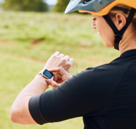 Téléchargez les photos : Smartwatch, fréquence cardiaque et femme cycliste vérifier le pouls extérieur pour le vélo et le vélo fitness. Exercice, app bien-être et athlète féminine faisant un contrôle de temps pour la course à vélo dans la nature par herbe. - en image libre de droit