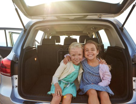 Prêt pour une aventure en road trip. deux petites filles assises dans le coffre d'une voiture