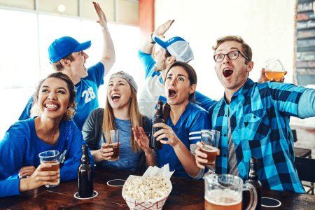 Foto de Amantes de los deportes fuertes y orgullosos. un grupo de amigos animando mientras ve un partido de deportes en un bar - Imagen libre de derechos