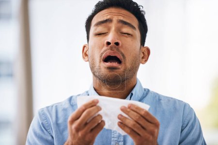 Sick, sneeze and man with a tissue, allergies and sickness with symptoms, cold and illness. Male model, person and guy with congested with sinuses, toilet paper for nose and fever with health issue.-stock-photo