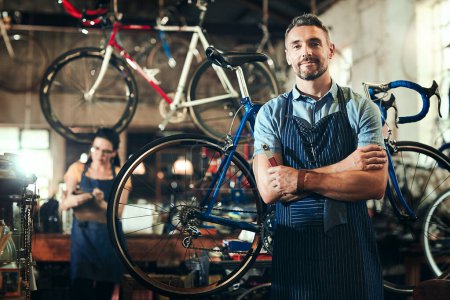 What can I do for you and your bike. Portrait of a mature man working in a bicycle repair shop with his coworker in the background