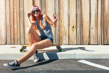 Photo for Dont be a hater, be a skater. a young woman sitting on her skateboard on a sidewalk - Royalty Free Image