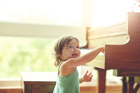 Photo for Mini maestro in the making. an adorable little girl playing on the piano at home - Royalty Free Image