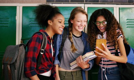 Photo for Where did you find this. a group of young school kids browsing on a cellphone together while waiting to go to class inside of a school - Royalty Free Image