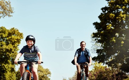 Foto de Hay un día divertido y soleado por delante. un niño y su padre montando juntos en sus bicicletas - Imagen libre de derechos