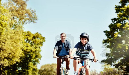 Foto de Disfrutando de un paseo con papá. un niño y su padre montando juntos en sus bicicletas - Imagen libre de derechos