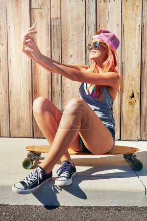 Photo for Just taking pics with my longboard. a young woman taking a selfie while sitting on her skateboard - Royalty Free Image