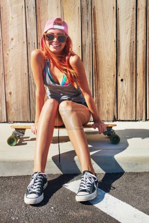 Photo for Wanna hang out. a young woman sitting on her skateboard on a sidewalk - Royalty Free Image