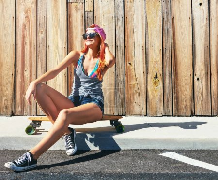Photo for Summertime is here and so is skateboarding time. a young woman hanging out on the boardwalk with her skateboard - Royalty Free Image
