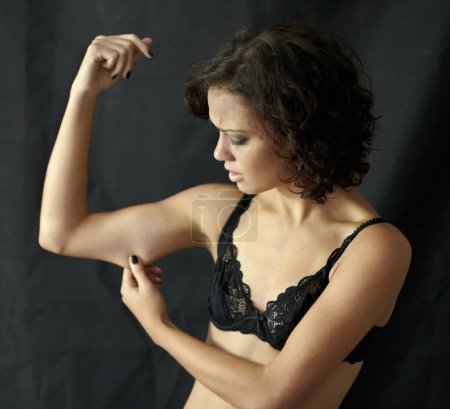 Foto de Anorexia, bulimia y mujer revisando su brazo en estudio por peso, obsesión y depresión sobre fondo negro. Trastorno alimenticio, enfermedad mental y niña que sufre ansiedad, dismorfia corporal o disgusto. - Imagen libre de derechos