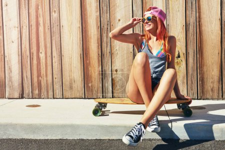Photo for Smile because you can. a young woman sitting on her skateboard on a sidewalk - Royalty Free Image