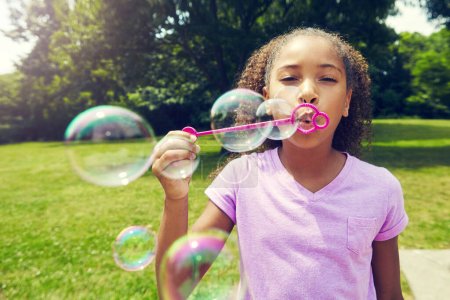 Photo for I love blowing bubbles. a little girl blowing bubbles outdoors - Royalty Free Image