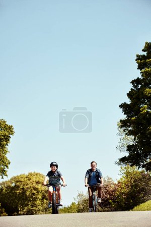 Foto de Es divertido y te mantendrá en forma. un niño y su padre montando juntos en sus bicicletas - Imagen libre de derechos