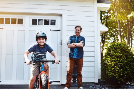 Foto de Papás orgullosos de la habilidad que le enseñó a su hijo. un niño montando una bicicleta con su padre en el fondo - Imagen libre de derechos