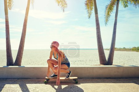 Photo for Learn to longboard. a young woman hanging out on the boardwalk with her skateboard - Royalty Free Image