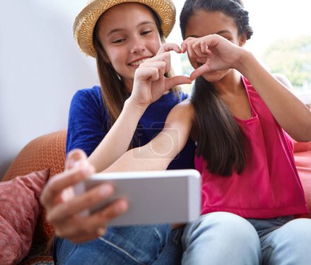 Téléchargez les photos : Faisons un selfie cardiaque. deux amis adolescents prenant un selfie tout en faisant une forme de coeur avec leurs mains - en image libre de droit