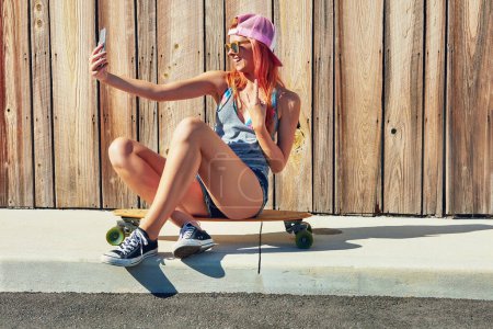 Photo for Selfie game on point. a young woman taking a selfie while sitting on her skateboard - Royalty Free Image