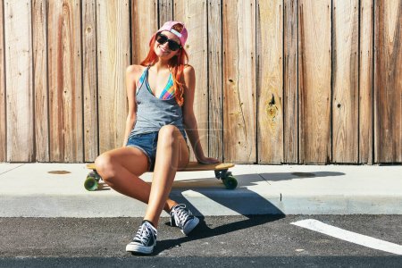 Photo for Be different, babe. a young woman sitting on her skateboard on a sidewalk - Royalty Free Image