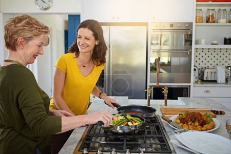 Téléchargez les photos : Légumes sont le plat d'accompagnement parfait pour n'importe quel repas. une femme âgée et sa fille cuisinent dans la cuisine - en image libre de droit