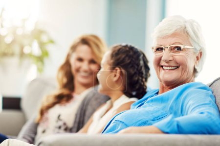 I love it when my family comes to visit. Cropped portrait of a senior woman sitting on the sofa at home with her daughter and granddaughter Poster 653762072