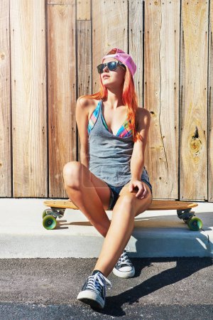 Photo for Skating gives me confidence. a young woman hanging out on the boardwalk with her skateboard - Royalty Free Image