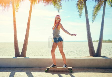Photo for Im walking on sunshine. a young woman hanging out on the boardwalk with her skateboard - Royalty Free Image