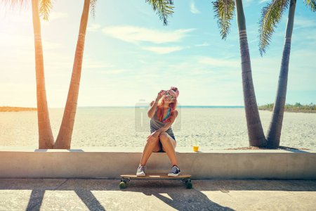 Photo for The promenade is where Ill be this summer. a young woman hanging out on the boardwalk with her skateboard - Royalty Free Image
