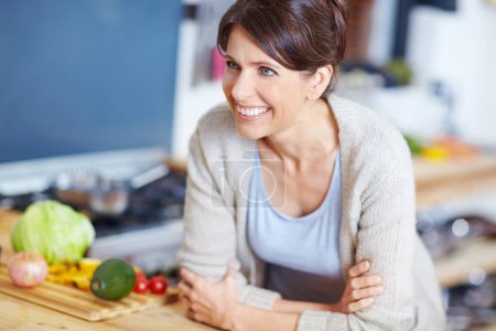 Photo for Contemplating which recipe to use. an attractive woman leaning on a kitchen counter filled with vegetables - Royalty Free Image