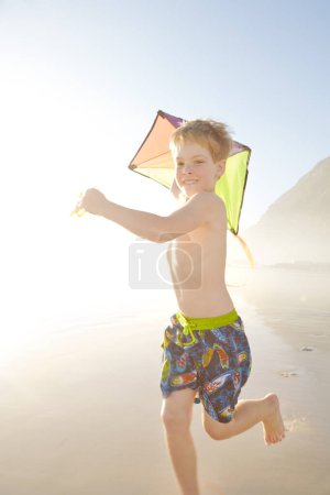 Téléchargez les photos : Comment puis-je obtenir cela dans l'air. un petit garçon courant tout en tenant un cerf-volant sur une plage - en image libre de droit