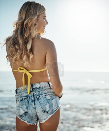Foto de Los días en la playa son días bien pasados. Vista trasera de una atractiva joven disfrutando de su día en la playa - Imagen libre de derechos