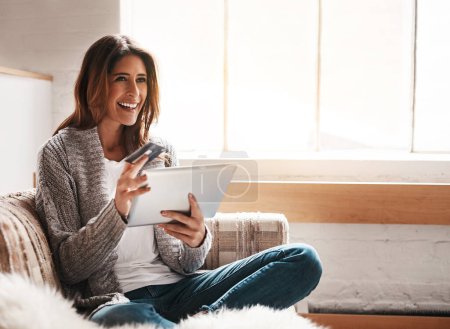 An online shopper in her element. an attractive young woman using a digital tablet and credit card on the sofa at home mug #654035840